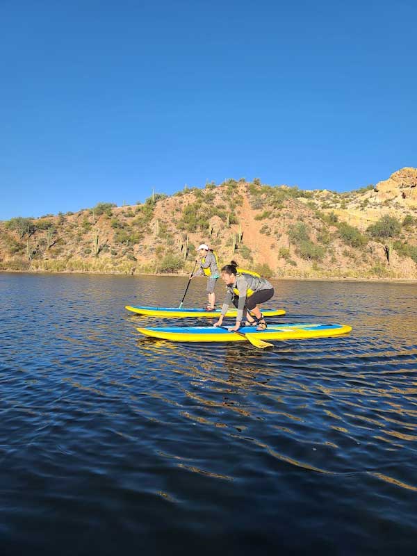 Two ladies taking paddleboarding lessons at Saguaro Lake by Riverbound Sports.